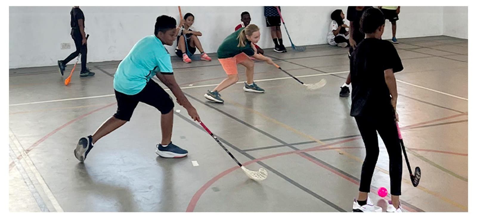 A group of students playing floorball together during a Hockey Jams lesson