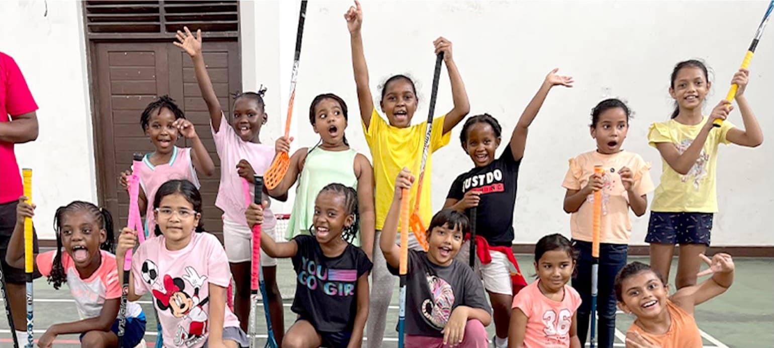 A group of students cheering with their floorball sticks raised
